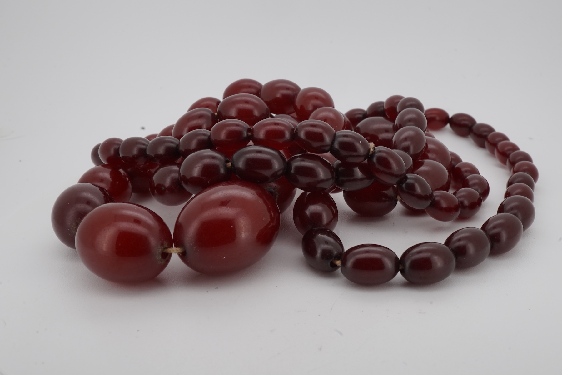 A cherry-coloured bakelite simulant amber necklace, composed of graduated beads measuring approximately 8-28mm, length 86cm, gross weight approximately 61 grams